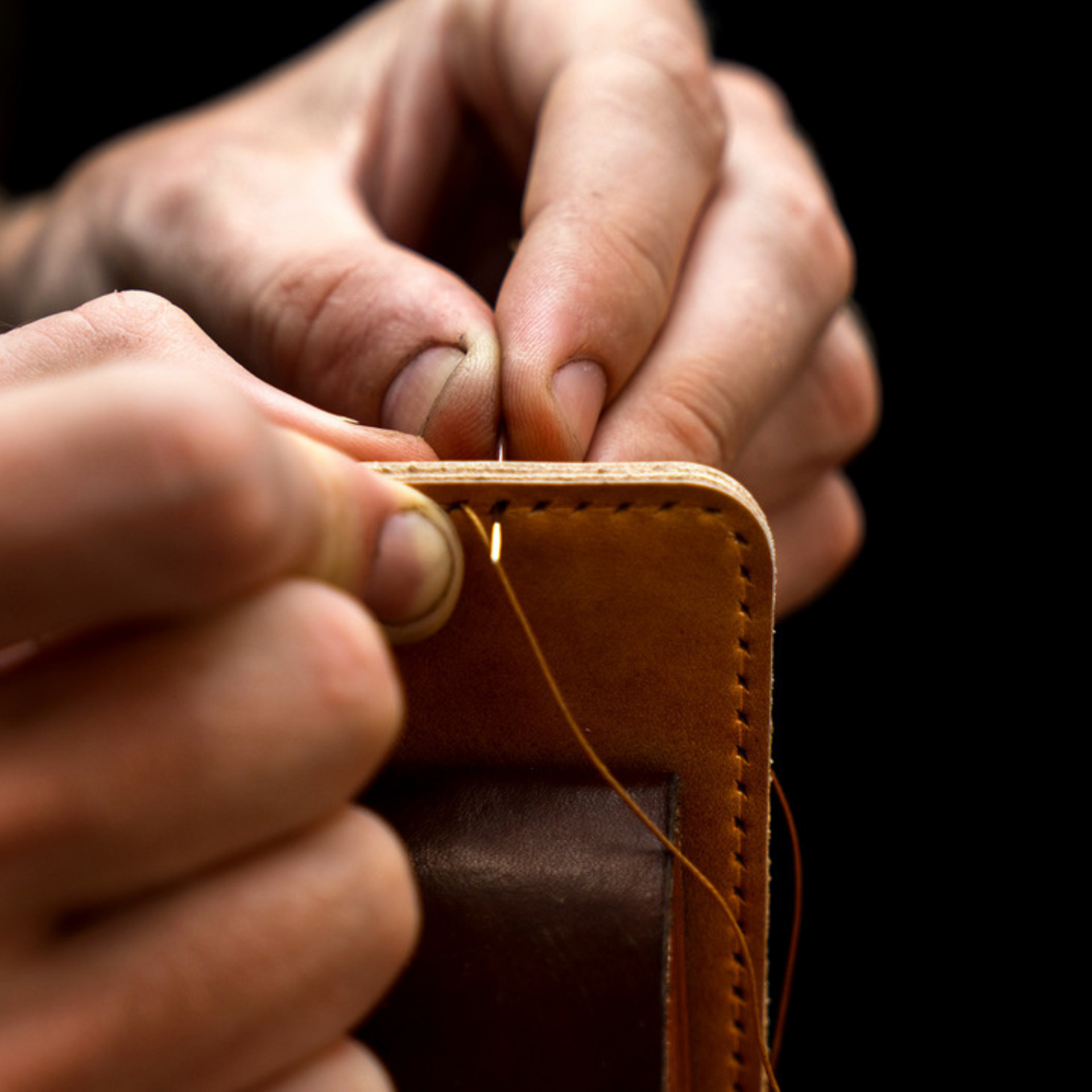 image showing a man's hand sewing a high-quality leather belt for a dog brush.